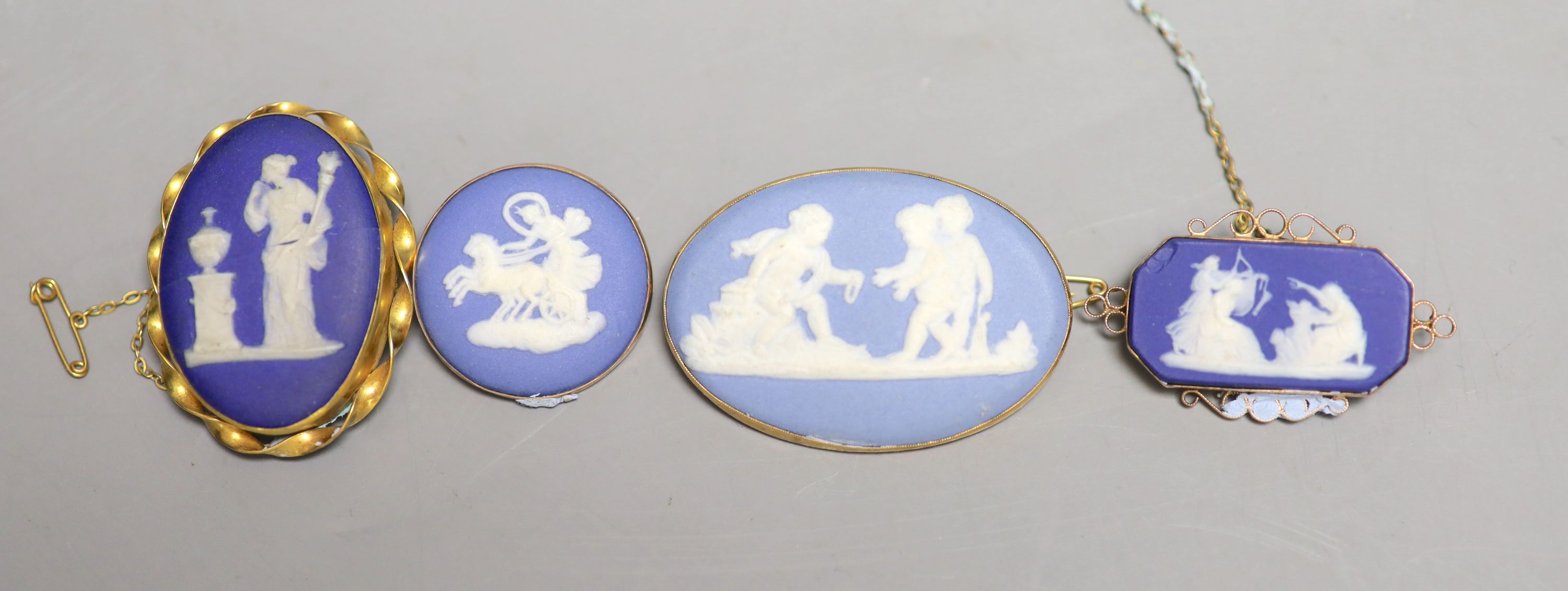 Four assorted late 19th/early 20th century yellow metal mounted Wedgwood plaque brooches.